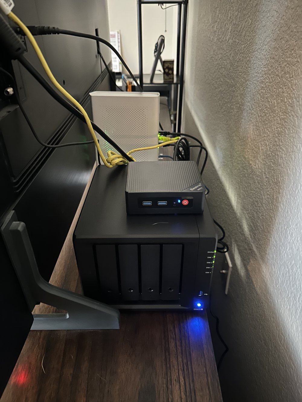 A Beelink mini PC sitting on top of a Synology NAS, status LEDs glowing